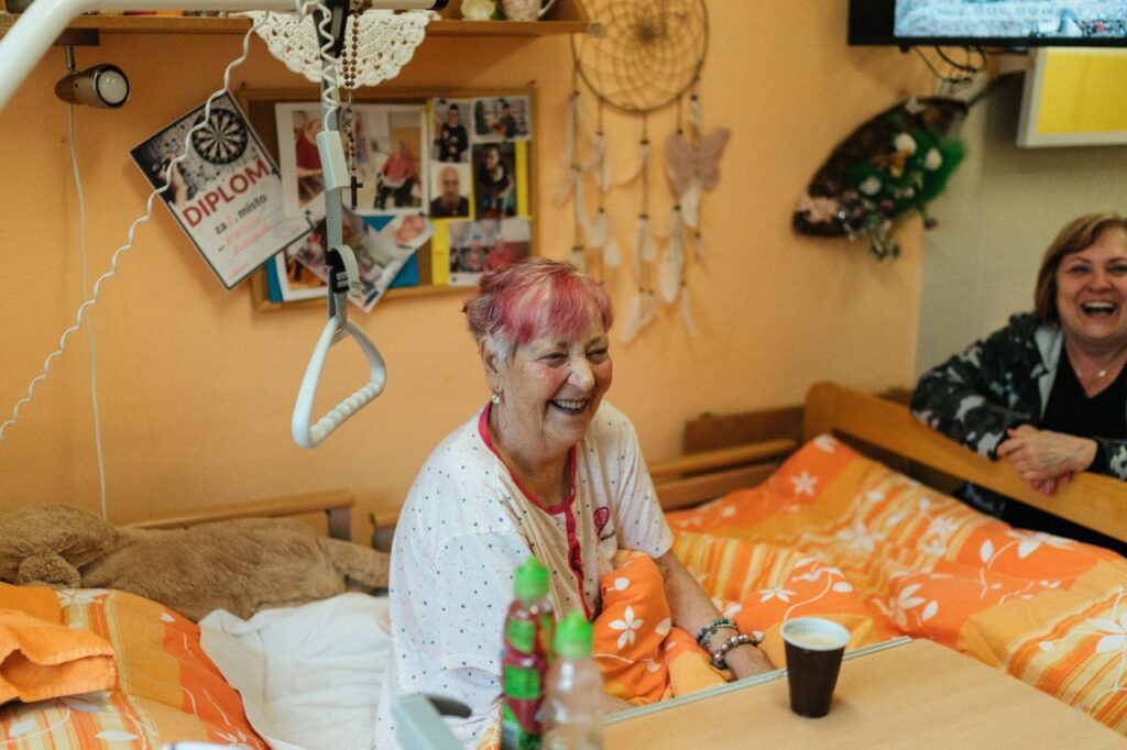 Cheerful elderly women sharing a light moment in a cozy hospital room.